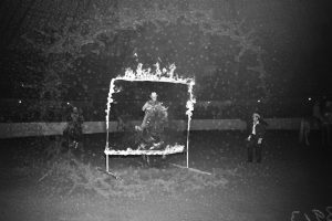 A performer jumps through a flaming hoop.