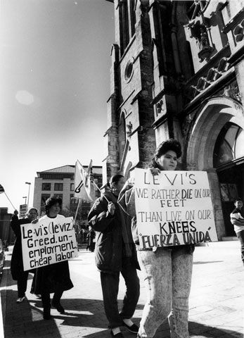 A black and white image of protestors holding signs in front of San Fernando Cathedral